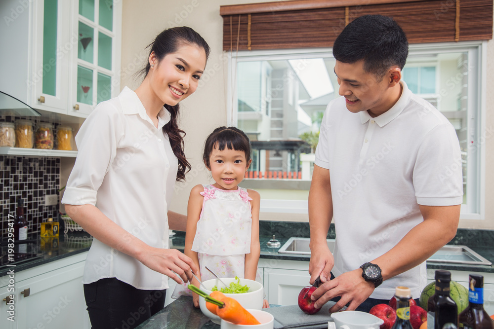 父亲、母亲和女儿一起做饭，这张照片可以用于家庭、食物、厨房