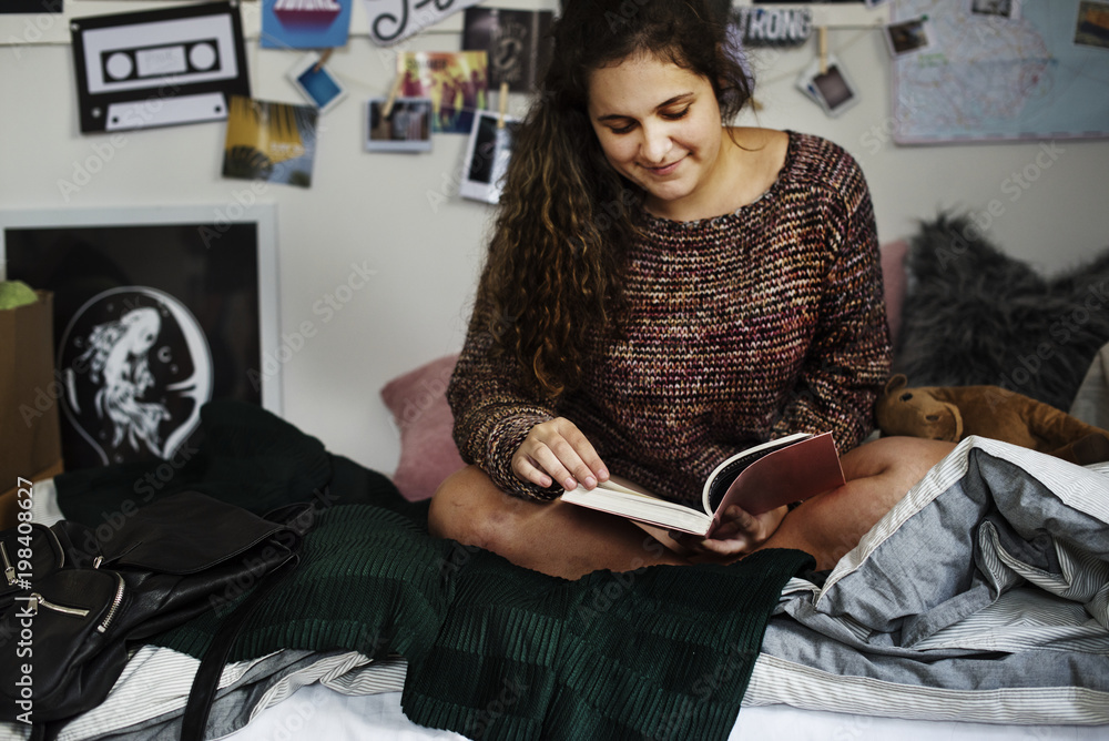 Teenage girl reading a book in a bedroom