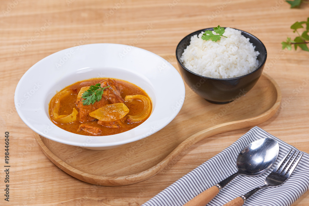 Tasty dinner with chicken curry in bowl on wooden background