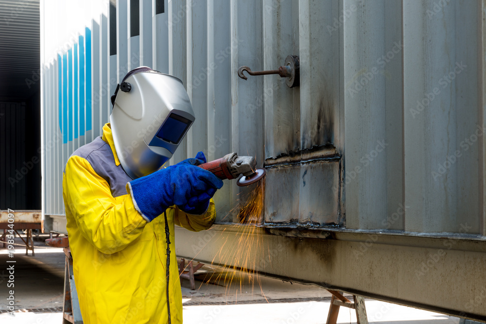 Industry worker with grinding metal to repair container structures manufacture workshop. Worker grin