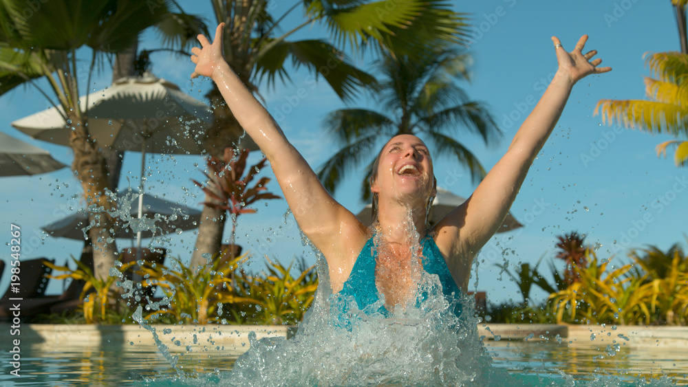 CLOSE UP: Submerged tourist outstretches her arms and stands up out of water.