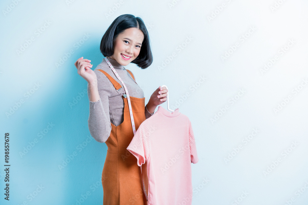 Asian girl designer is showing off the shirt she is designing.