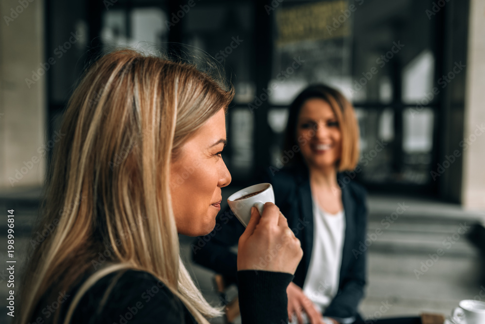 大笑的年轻女商人喝咖啡的侧视图。做鬼脸。