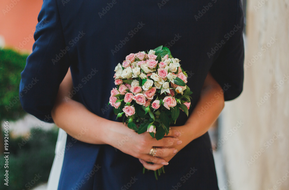 Beautiful wedding couple is hugging near the orange ancient stone walls. Bride in satin lace dress i