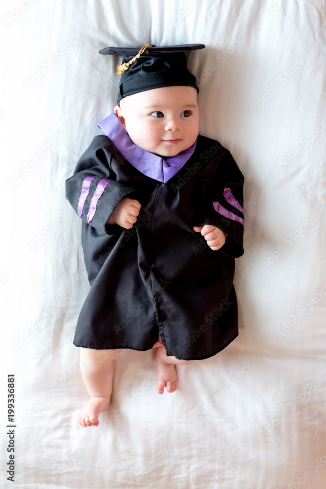 Little baby girl in graduation cap and gown