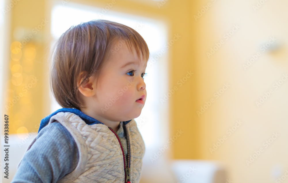 Toddler boy in his house looking into the distance