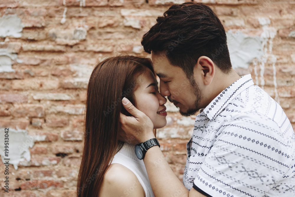 Lovely asian couple by a brick wall