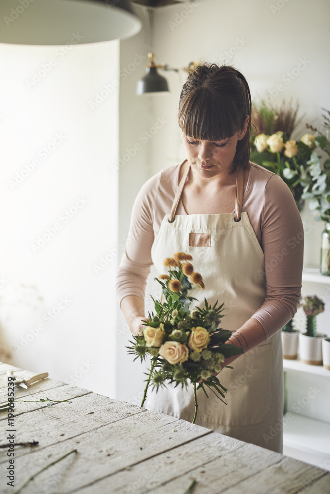 Young female florist making a flower bouquet in her workshop