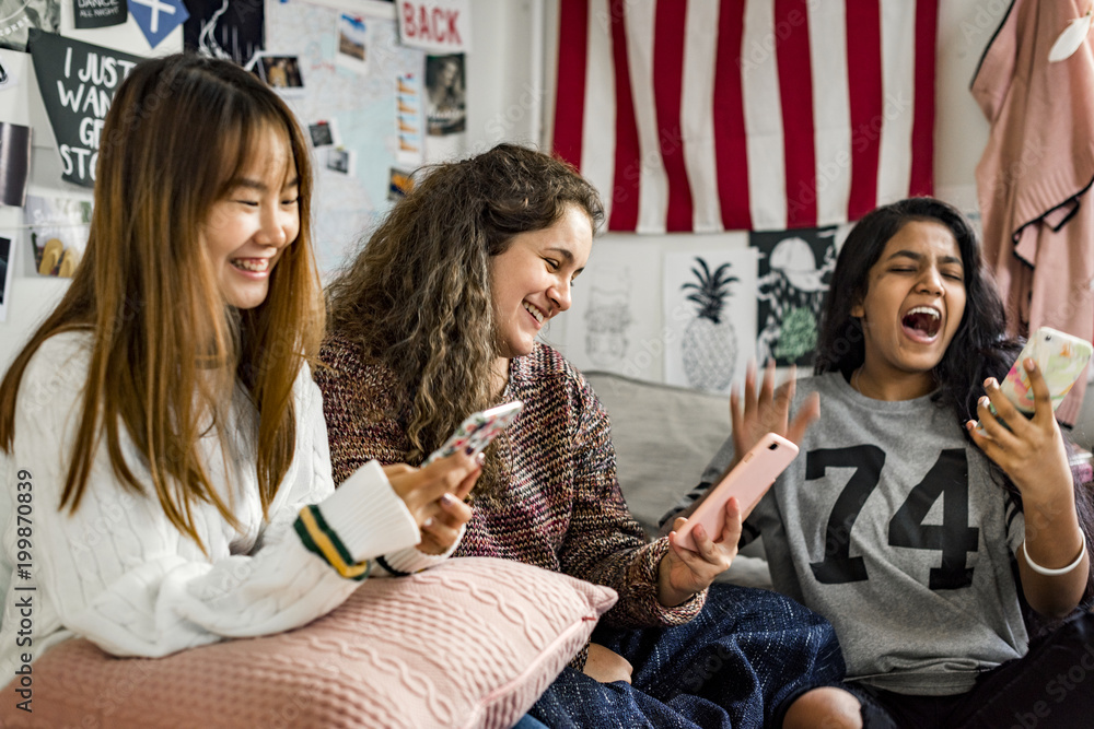 青少年女孩在卧室里使用智能手机参加睡眠派对