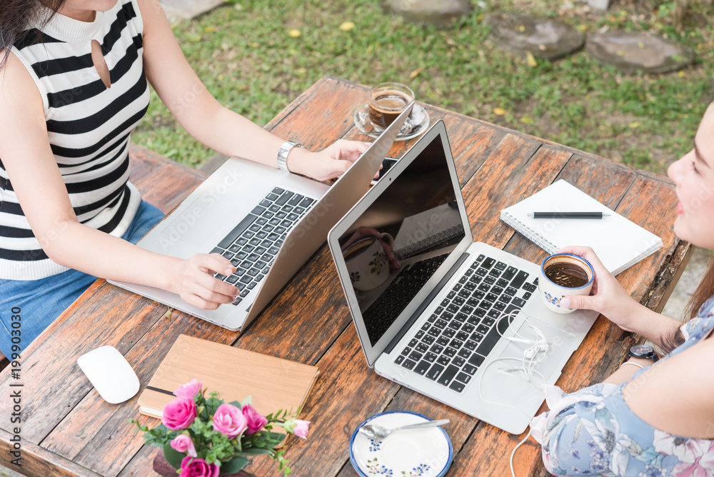 Two teenage women meet in coffee shop use laptop together in afternoon, life style of new teenager