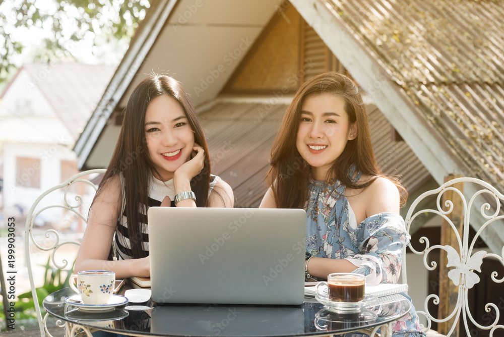 Two teenage women meet in coffee shop use laptop together in afternoon, life style of new teenager