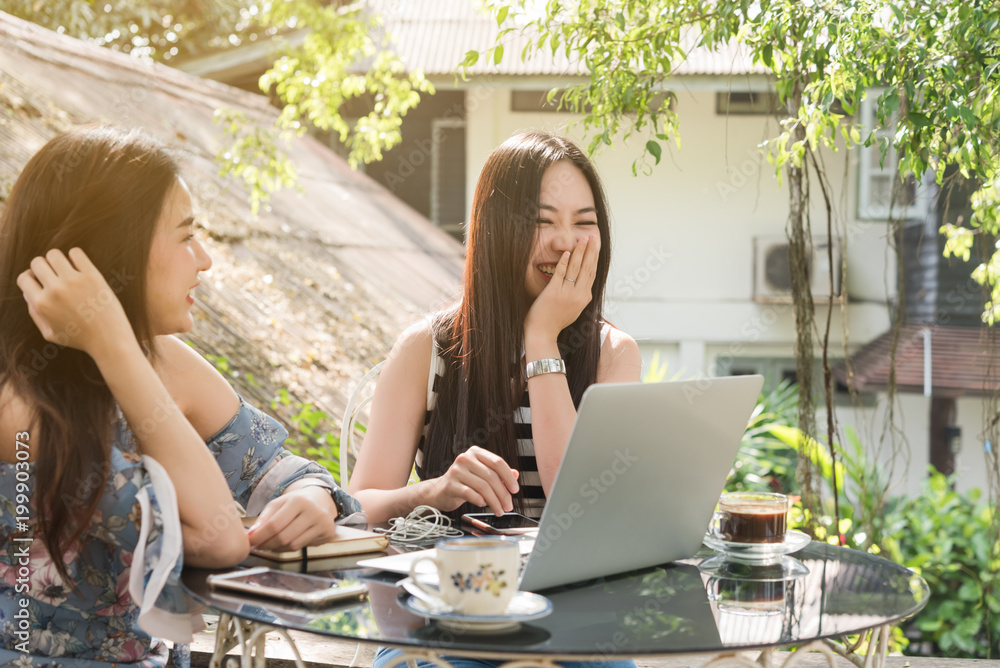 Two teenage women meet in coffee shop use laptop together in afternoon, life style of new teenager