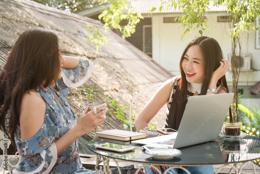 Two teenage women meet in coffee shop use laptop together in afternoon, life style of new teenager