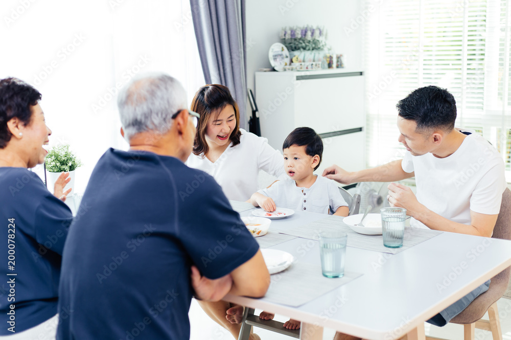 快乐的亚洲大家庭在家共进晚餐，充满欢笑和幸福