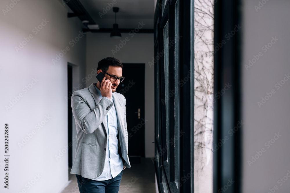 Businessman having a phone call in the office building corridor