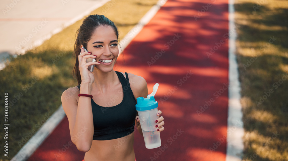 乐观的漂亮女孩慢跑后打电话。