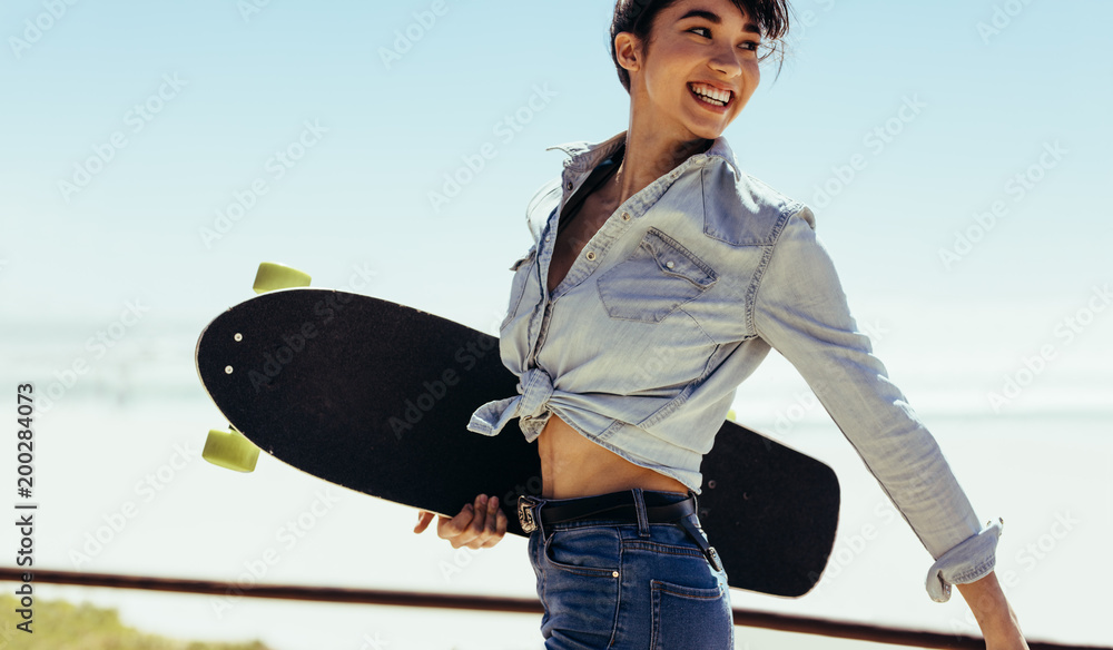 Woman walking outdoor on summer day with a skateboard