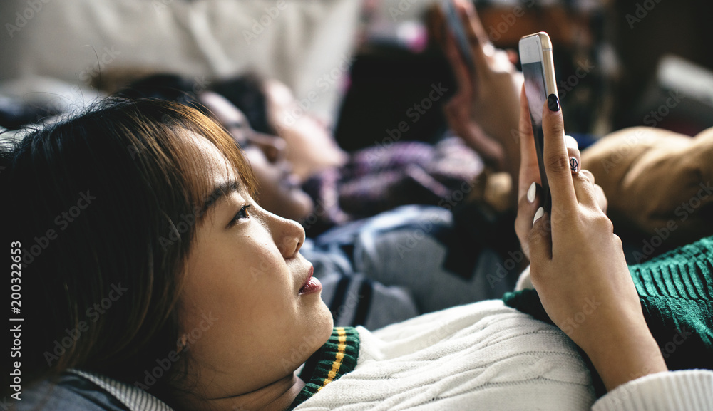 青少年女孩在床上使用智能手机参加睡眠派对