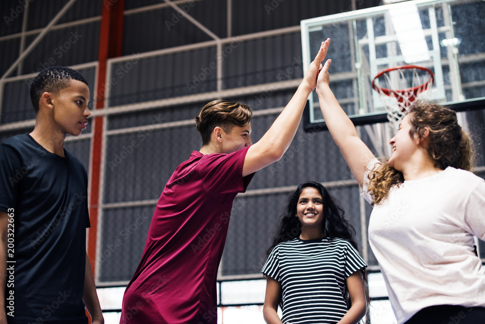 Group of teenager friends on a basketball court giving each other a high five