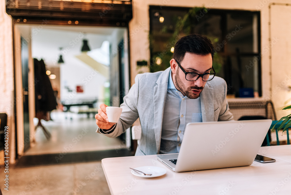 Surprised businessman looking at laptop screen at the cafe.