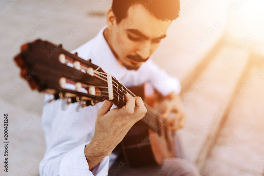 Male musician playing guitar outdoors. Close-up.