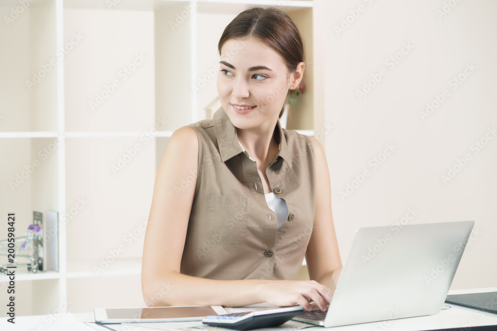 Woman thinks and works on computer in office.