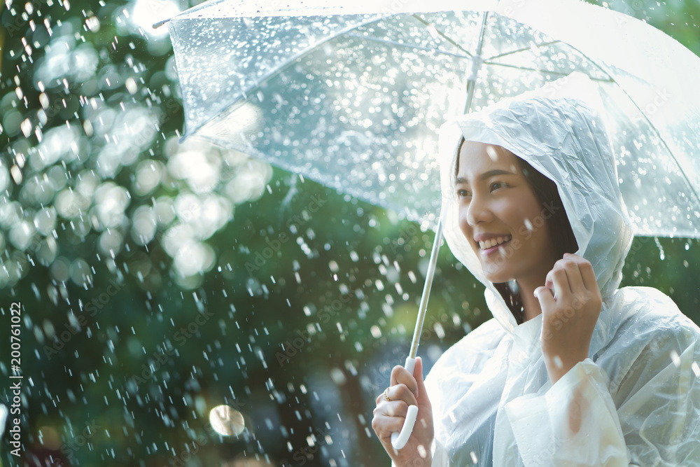 雨天亚洲女人在户外穿着雨衣。她很开心。