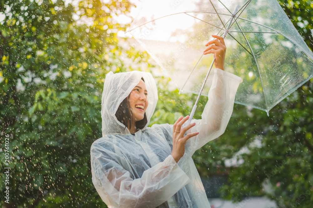 雨天，亚洲女人在户外穿着雨衣。她很开心。