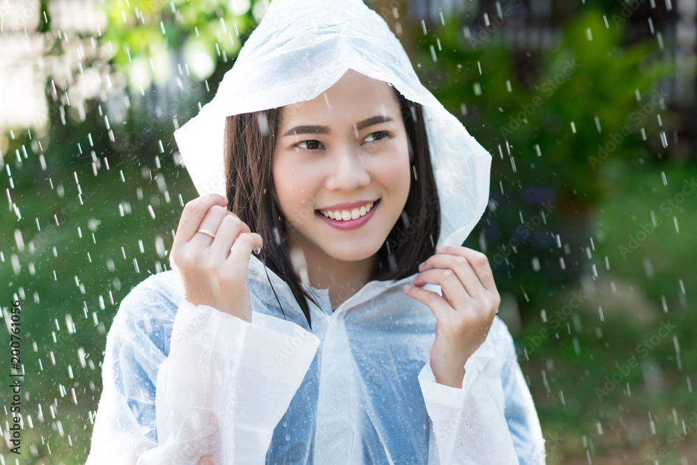 雨天，亚洲女人在户外穿着雨衣。她很开心。