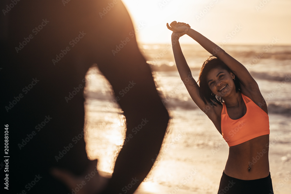 与教练在海滩锻炼的女性