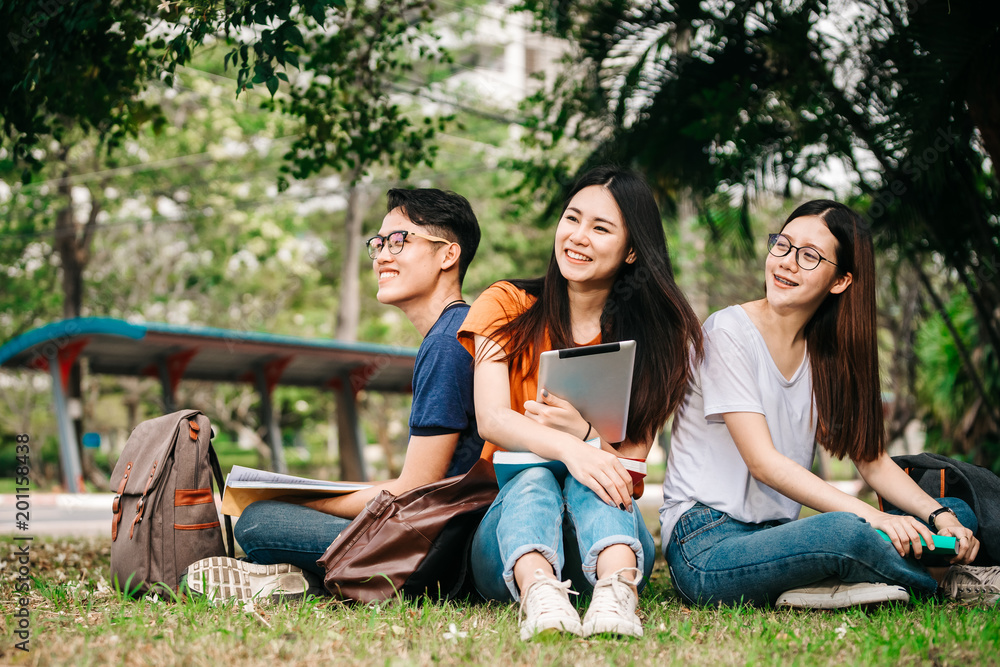 一群年轻或十几岁的亚洲大学生在大学里微笑着看书，看着ta