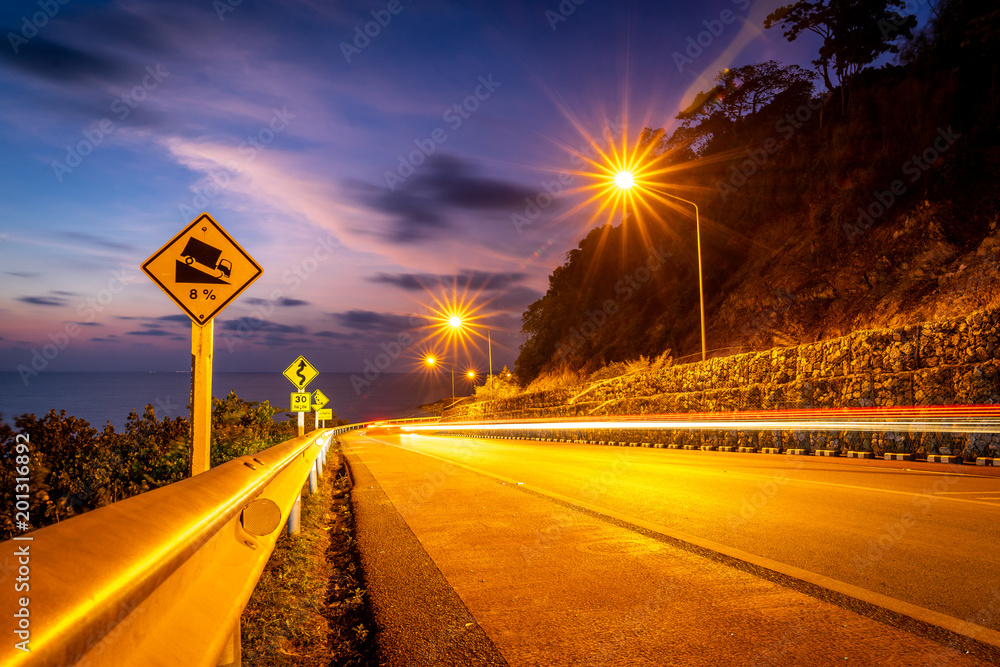 Thaila东部日落时与山相邻的海边道路上的安全警告标志