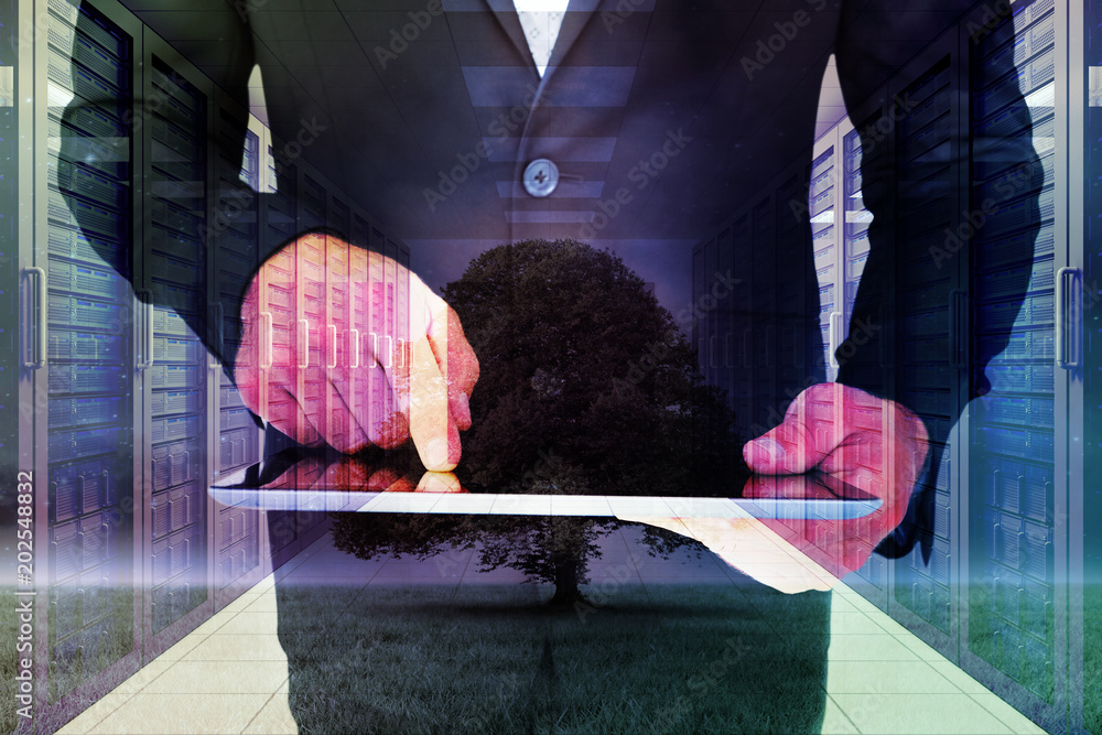 Businessman using his tablet pc  against tree in field at night