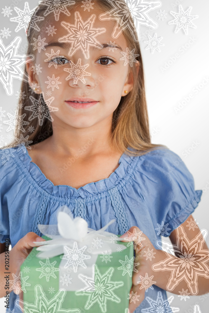 Composite image of Portrait of a smiling little girl holding a wrapped gift with snowflakes on silve