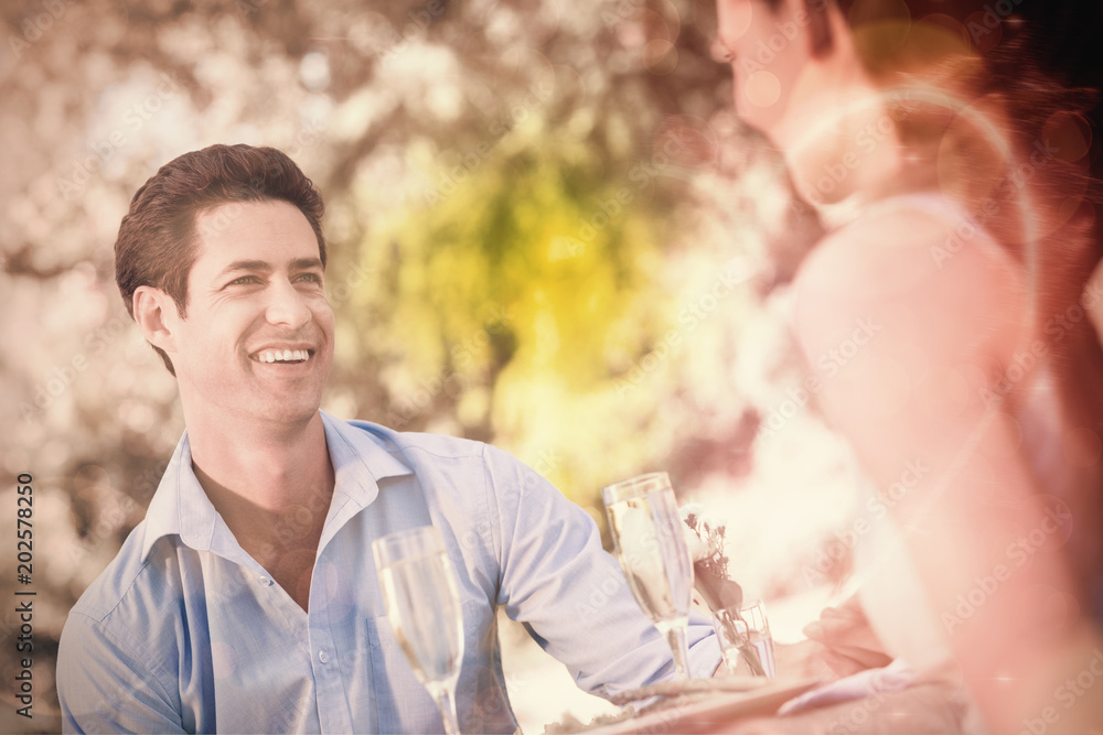 Smiling young couple with champagne flutes sitting at an outdoor caf√©