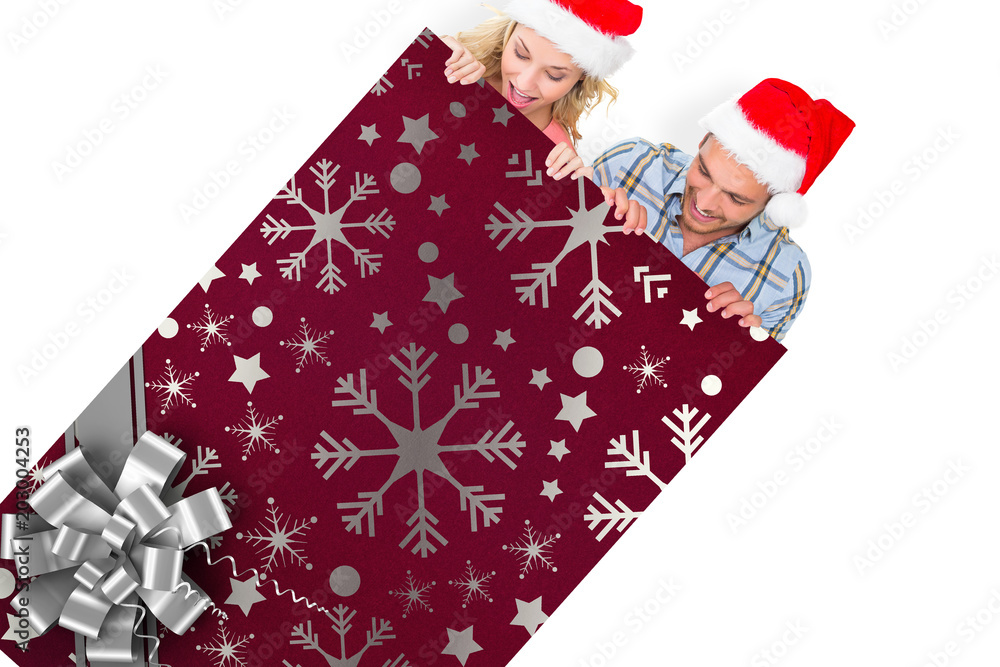 Young festive couple against christmas wrapping paper with bow