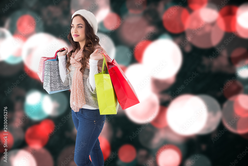 Brunette in winter clothes posing with shopping bags against blurry lights