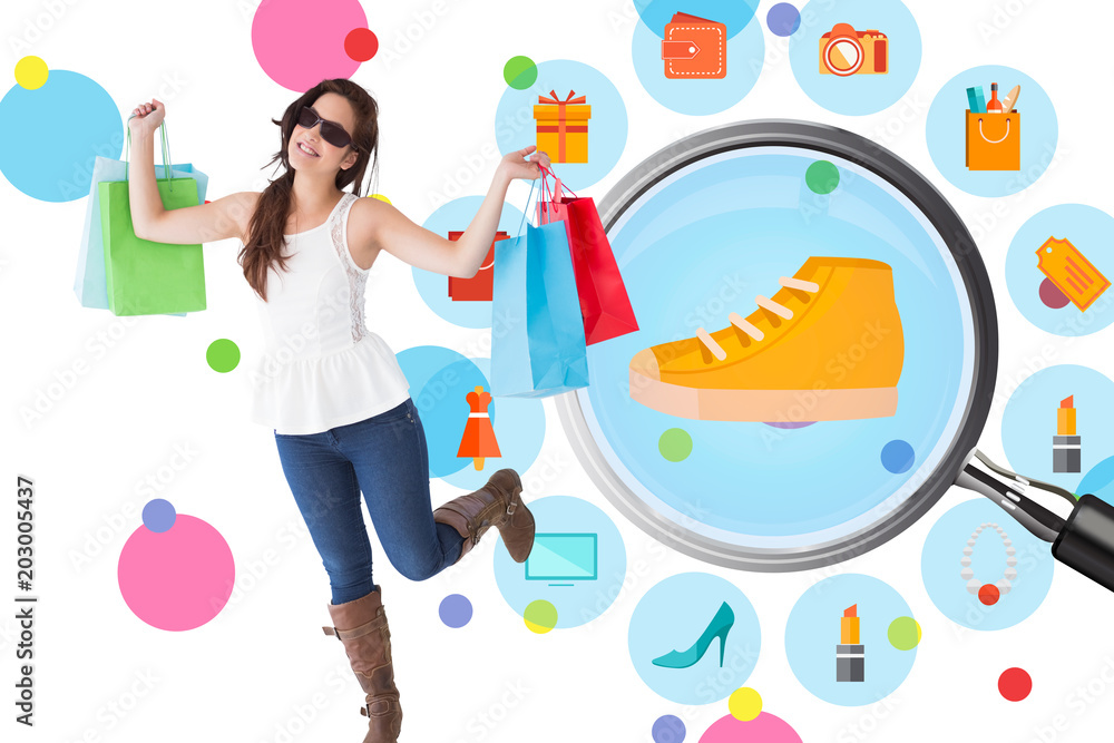 Happy brunette with sunglasses holding shopping bags  against dot pattern