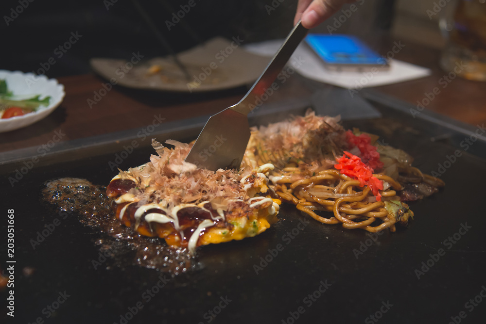 厨师烹饪okonomiyaki；日式煎饼或披萨