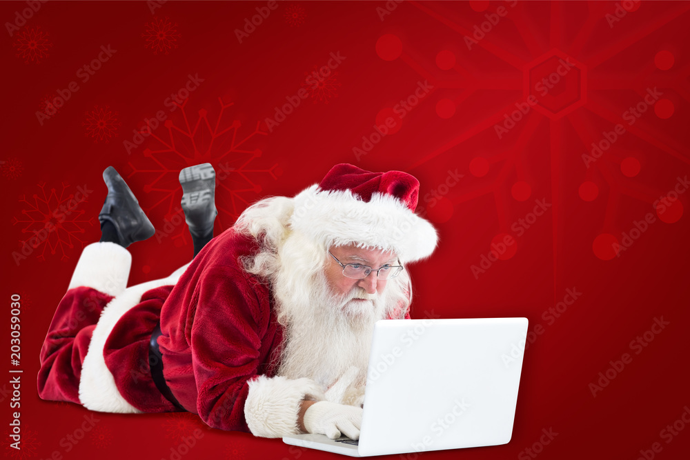 Santa lies in front of his laptop against red background