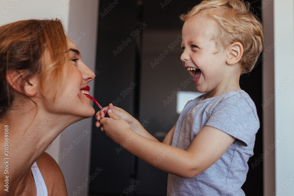 Little boy putting on makeup to her mother