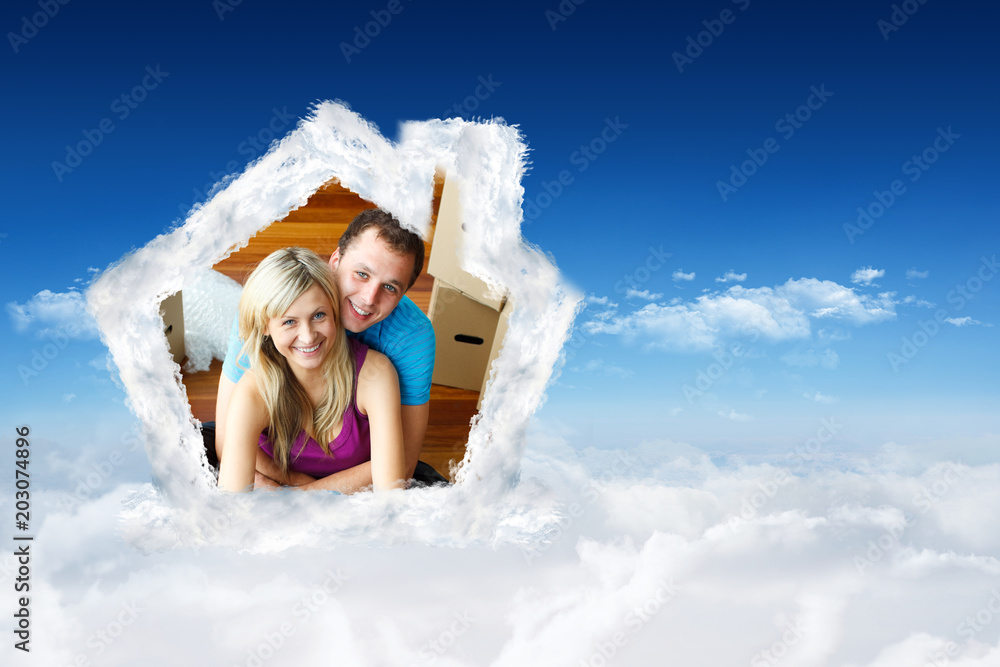 Happy couple sitting on floor handing a glass of champagne against bright blue sky over clouds