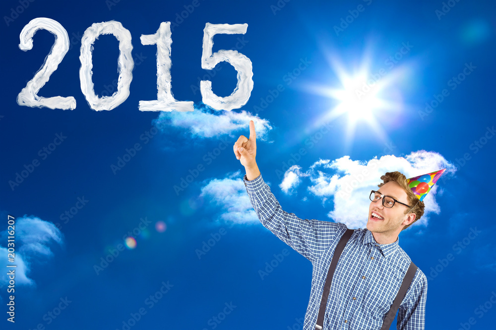 Geeky hipster wearing party hat pointing against bright blue sky with clouds