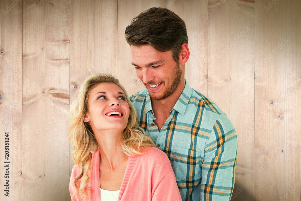 Attractive young couple embracing and smiling against wooden planks