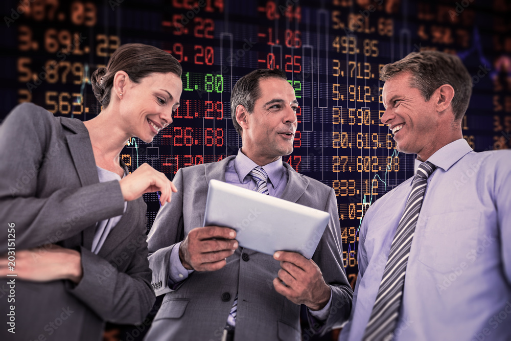 Businessman showing tablet to his colleagues  against stocks and shares