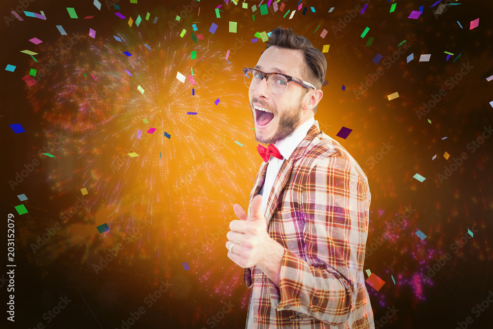 Geeky hipster pointing at camera against colourful fireworks exploding on black background