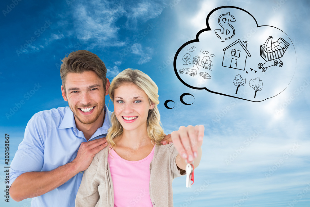 Attractive young couple showing new house key against blue sky