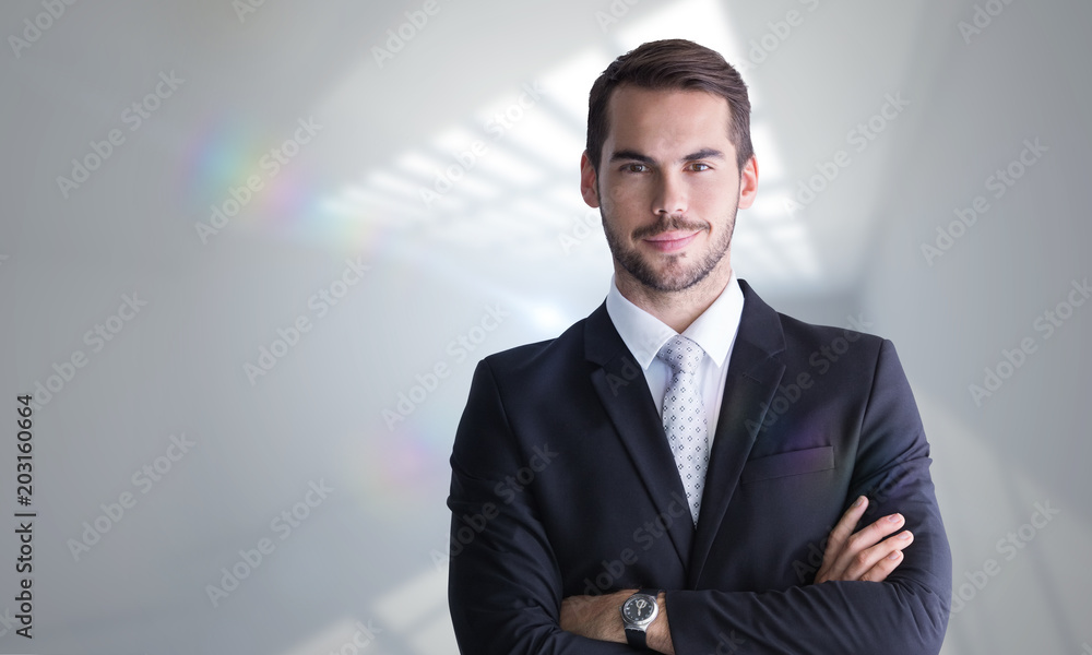 Smiling businessman posing with arms crossed against room with windows at ceiling