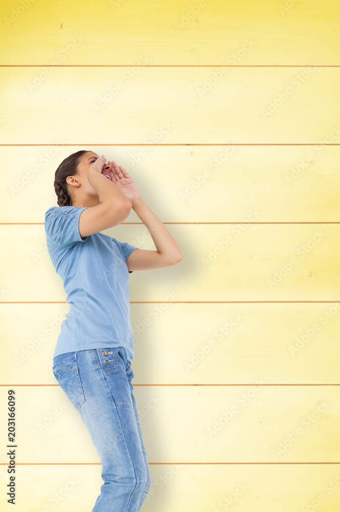 Pretty brunette shouting against wooden background in yellow