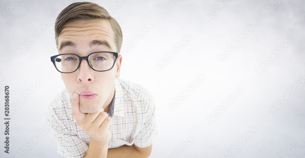 Geeky hipster thinking with hand on chin against white wall